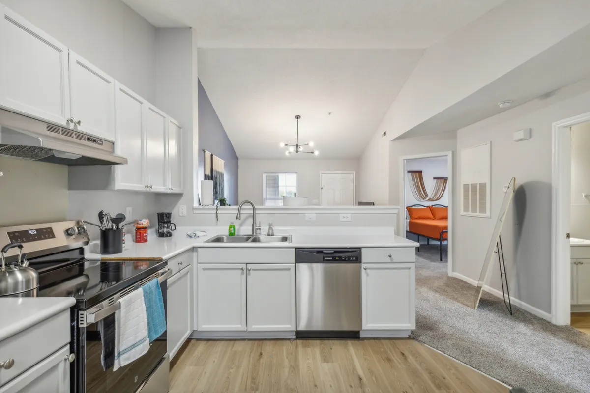 This image showcases a modern kitchen featuring a prominent kitchen island, gleaming stainless steel appliances, and a stylish overhead light fixture. The open layout suggests ample counter space and an inviting atmosphere suitable for cooking and social gatherings.