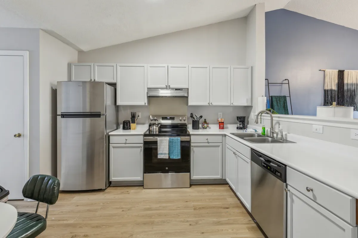 This cozy kitchen scene features stainless steel appliances, crisp white cabinetry, a kitchen island, and a striking blue accent wall. The space is designed for both function and comfort, making it ideal for anything from holiday dinners to morning coffee.