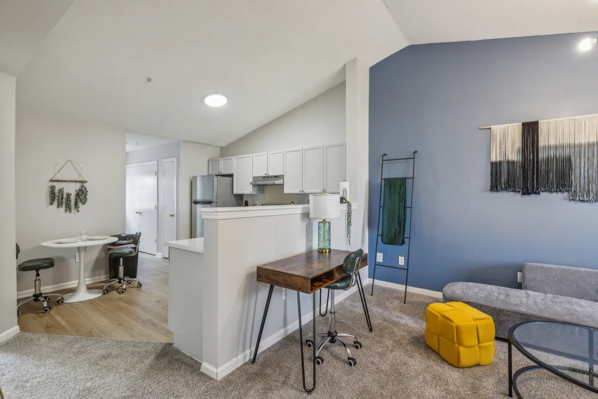 A cozy kitchenette and seating area, complete with a decorative wall hanging and workspace. The space is modern, tidy, and versatile, offering guests a glimpse of the apartment's practical amenities and comfortable environment ideal for everyday living.